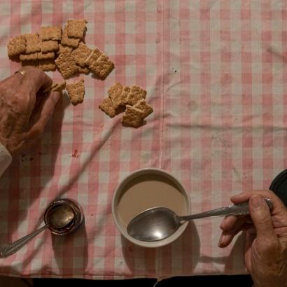 an elderly man eats alone at table in San Fiorano, Italy