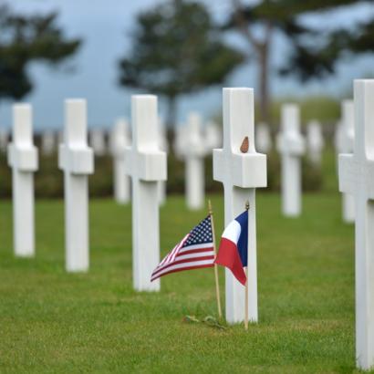 gravestones with US and French flags at the Normandy American Cemetery and Memorial in Colleville-sur-Mer, Normandy, France.