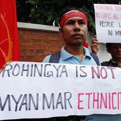 Burmese nationalist protester holding banner denying Rohingya ethnicity