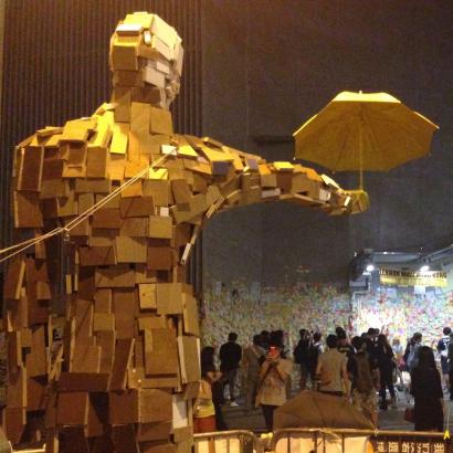 photo of “Umbrella Man” by Hong Kong artist Milk, with Post-It note covered “Lennon Wall.”