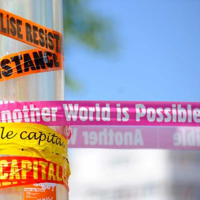 tape with words related to neoliberalism attached to a pole