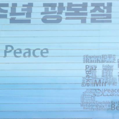 South Korean minister at conference podium with backdrop showing word Peace in numerous languages