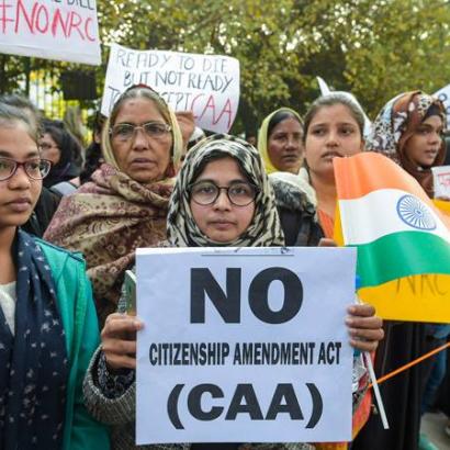 Indian women gathered in protest hold up an anti-CAA banner