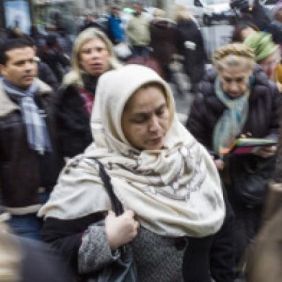 headscarf-clad woman moves through a crowded street in Europe
